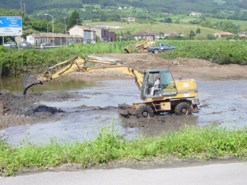 Excavadora retirando tierra en terreno con agua