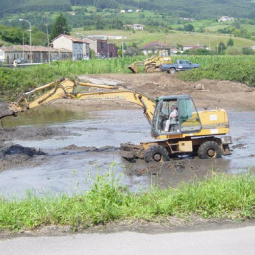 Excavadora retirando tierra en terreno con agua